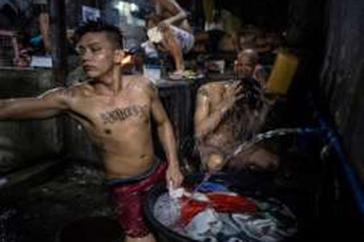 Begitu minimnya ruang di dalam Lapas Quezon City membuat para narapidana harus melakukan berbagai hal di tempat yang sama. Dalam foto ini terlihat seorang narapidana sedang memasak (tengah belakang), sementara yang lain mencuci dan mandi.