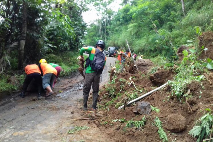 Petugas gabungan membersihkan material longsor di ruas jalan Banjarnegara-Karangkobar, Minggu (22/4/2018).