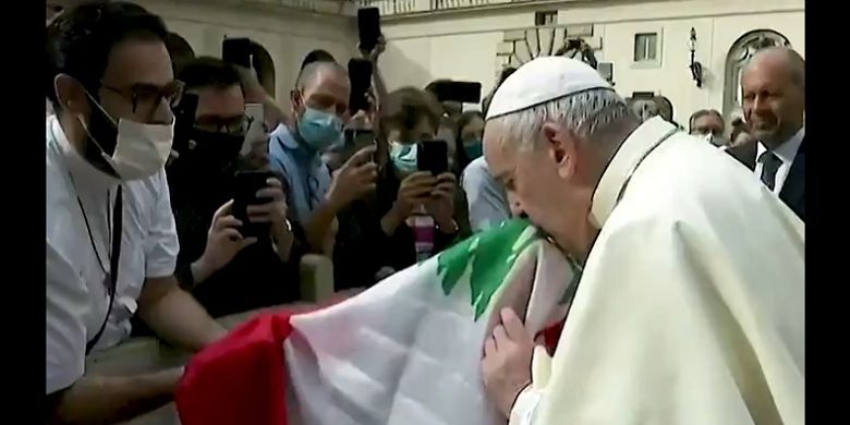 Sri Paus Fransiskus tampak mencium bendera Lebanon yang disodorkan seorang pastor dalam audiensi umum.