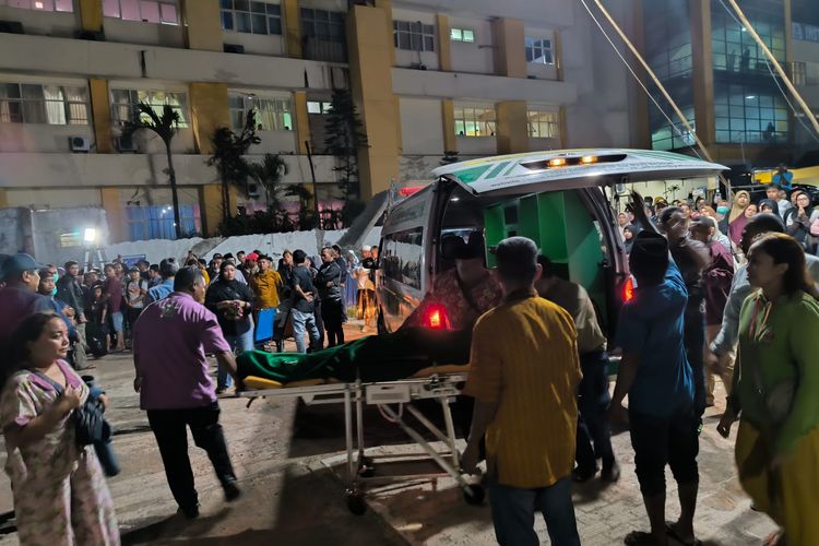 Para petugas menurunkan jenazah dari ambulans untuk dishalatkan secara massal di hakaman parkir RS Bina Sehat Jember, Minggu (14/9/2025).