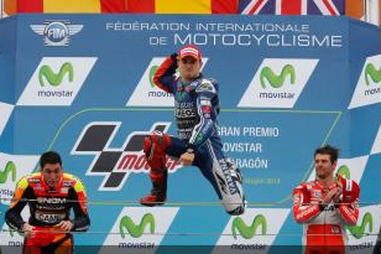 Pebalap Movistar Yamaha asal Spanyol, Jorge Lorenzo (tengah), melompat di atas podium untuk merayakan kemenangan pertamanya musim ini di GP Aragon, Minggu (28/9/2014). Pebalap Forward Racing, Aleix Espargaro (kiri) finis kedua, disusul pebalap Ducati, Cal Crutchlow.