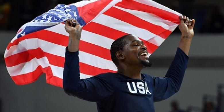 Kevin Durant mengibarkan bendera Amerika Serikat seusai timnya memenangi medali emas Olimpiade 2016 usai final versus Serbia, Minggu (21/8/2016). 