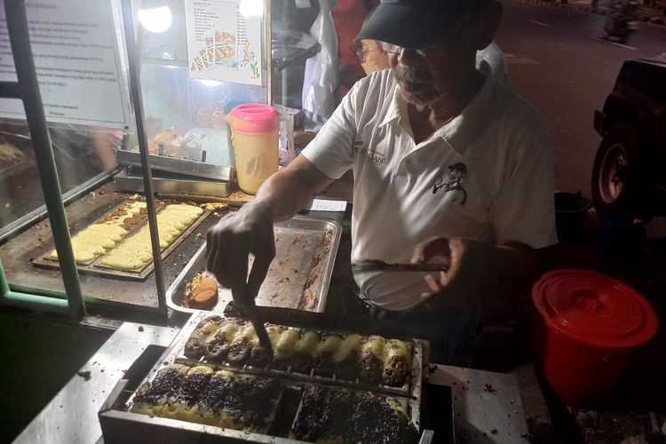 Pemilik Kue Pukis Petudungan, Mardjuki, sedang memasak kue pukis untuk pelanggan, Senin (18/12/2023).