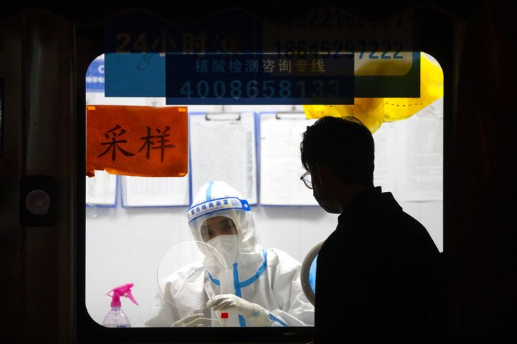 Seorang pekerja dengan pakaian pelindung menunggu untuk memberikan tes COVID-19 di tempat pengujian virus corona di Beijing, Rabu, 2 November 2022. 