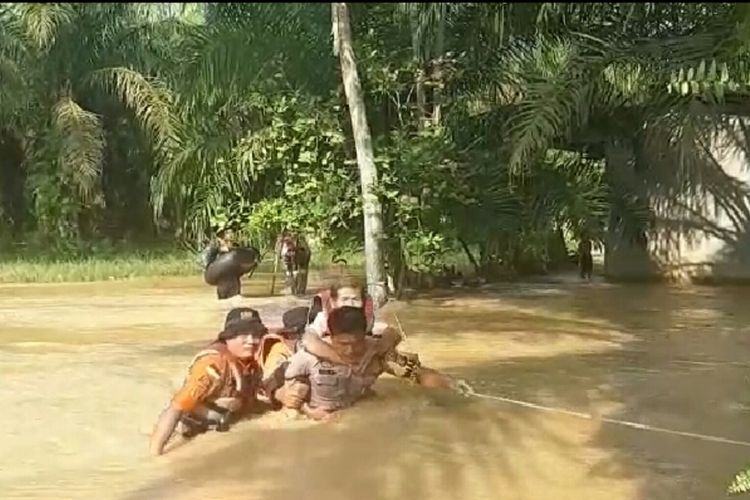 Bhabinkamtibmas Desa Pelanduk, Bripka Rido menggendong kakek Warjito untuk dievakuasi, yang melewati arus banjir yang sangat deras di Desa Pelanduk, Kecamatan Kunto Darussalam, Kabupaten Rohul, Riau, Senin (25/11/2019).