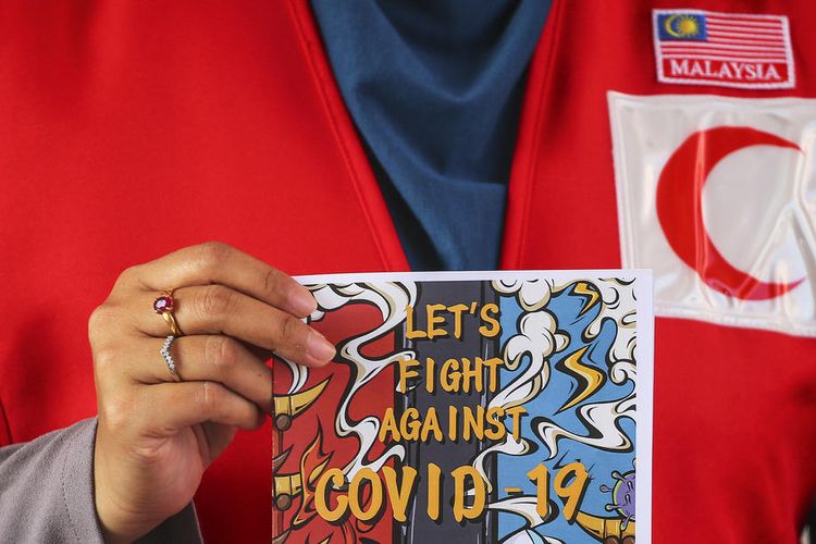Petugas Bulan Sabit Merah Malaysia memegang kartu pos bermakna Ayo Lawan Covid-19 di Putrajaya, Malaysia, 14 Maret 2020.