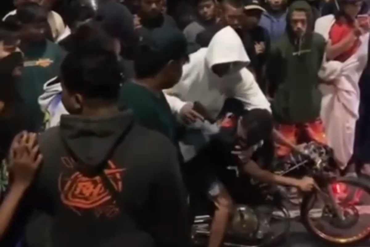 Sosok berbaju putih menodongkan benda mirip pistol ke pria pengendara sepeda motor yang diduga untuk balap liar. Potongan video penodongan pistol itu menjadi viral setelah viral di media sosial. 