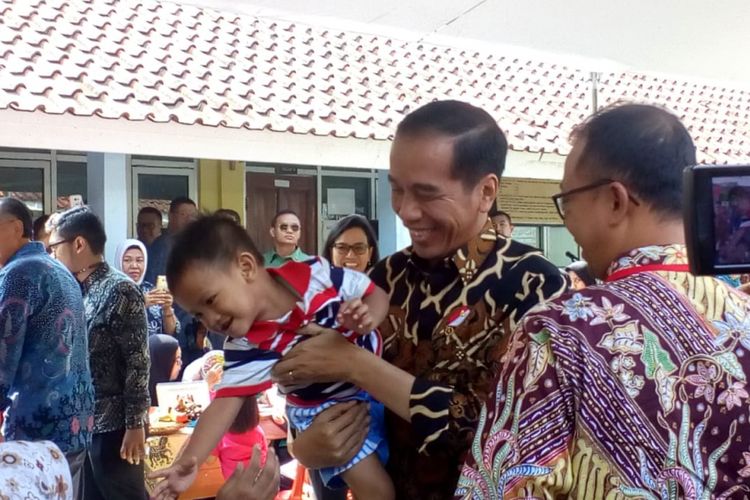 Presiden Joko Widodo menggendong seorang balita saat blusukan ke Posyandu di Desa Tangkil, Bogor, Rabu (4/7/2018).