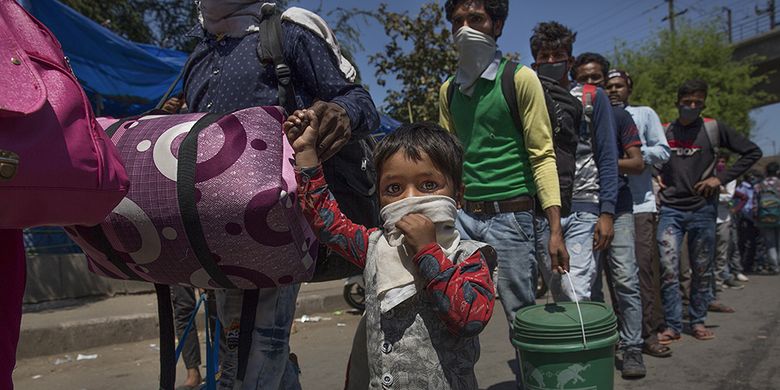 Buruh migran dalam antrean menunggu bus di sebuah terminal angkutan umum selama karantina wilayah (lockdown) di New Delhi, India, Minggu (29/3/2020). Pemerintah India pada 24 Maret lalu mulai memberlakukan lockdown selama 21 hari di seluruh wilayah negara itu dalam upaya mengendalikan penyebaran COVID-19.