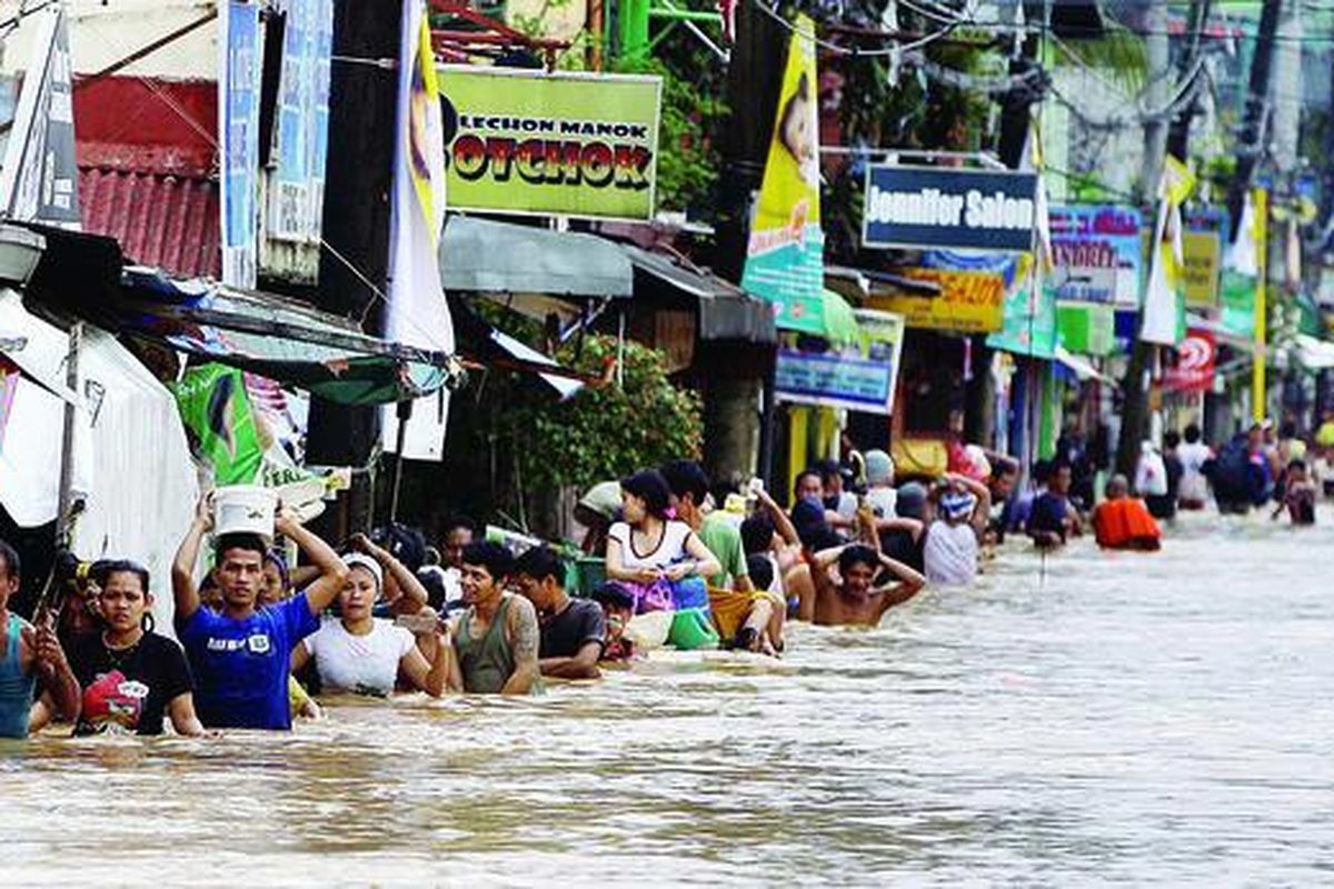Warga berbaris melewati jalan yang tergenang air di Marikina City di sebelah timur Manila, Filipina, Rabu (8/8). Banjir besar di negara itu telah menewaskan 23 orang dan membuat jutaan warga menderita. Tim penyelamat mengerahkan perahu-perahu karet untuk menyelamatkan ribuan warga yang masih terjebak di beberapa desa.