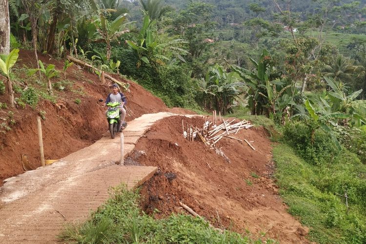Warga mengendarai sepeda motor melintas lokasi jalan yang sempat tergerus longsor di Kampung Ciseureuh, Desa Bojongkerta, Kecamatan Warungkiara, Sukabumi, Jawa Barat, Junat (7/2/2020).