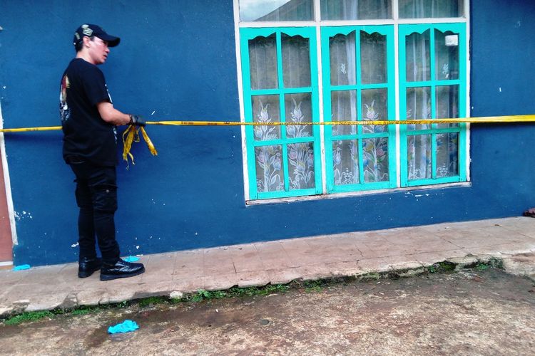 Seorang anggota polisi memasang garis pembatas di rumah tersangka Solihin di Cianjur, Jawa Barat. Di rumah ini ditemukan dua jenazah yang dikubur dalam satu lubang.