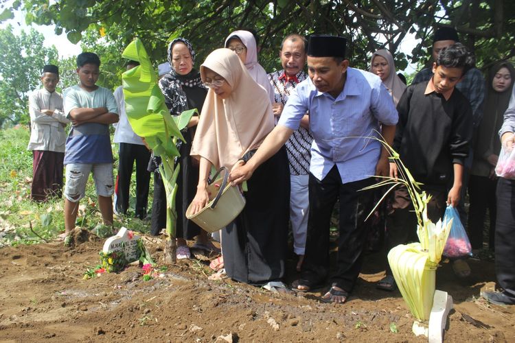 Orang tua Zidan menaburkan bunga saat pemakaman di Kelurahan Jogoyudan