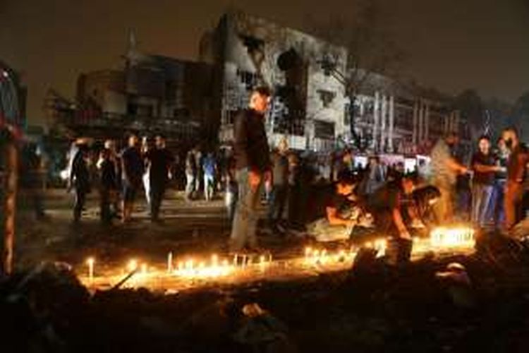 Warga berdoa dengan membakar lilin, Senin (4/7/2016), di lokasi korban ledakan bom di Baghdad, Irak yang menewaskan sekitar 213 orang, Minggu (3/7/2016).