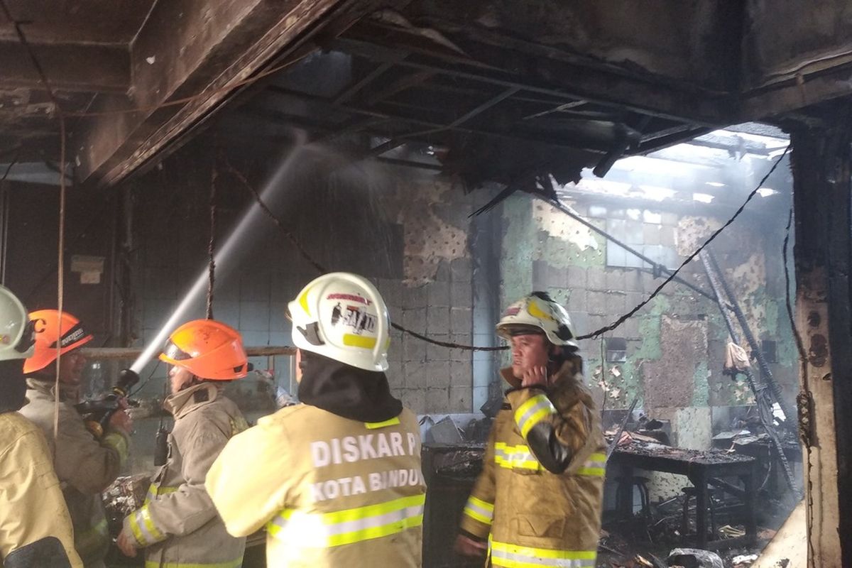 Sejumlah petugas pemadam kebakaran dari Diskar PB Kota Bandung sedang berupaya memadamkan kobaran api yang melahap ruko di depan Pasar Simpang Dago, Jalan Ir. H Juanda, Kota Bandung, Jawa Barat, Jumat (26/7/2024).