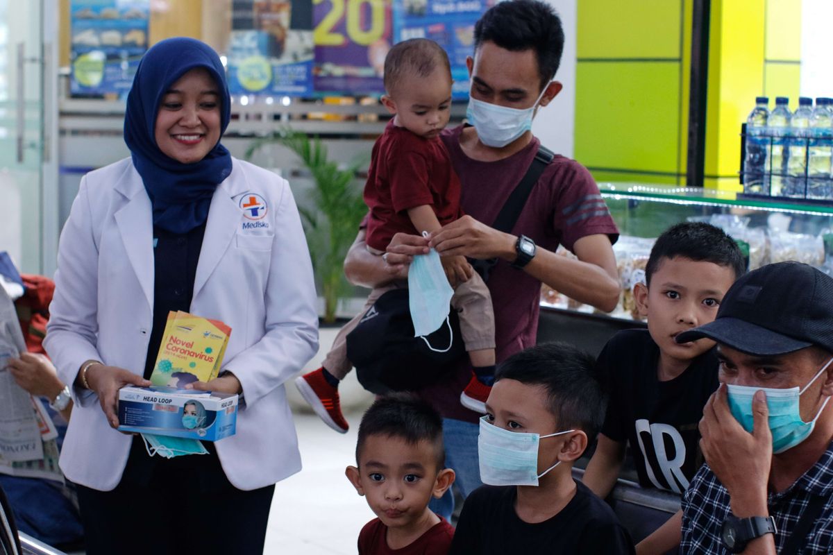 Petugas medis dari PT KAI DAOP 1 Jakarta membagikan masker pada calon penumpang kereta api di Stasiun Gambir, Jakarta, Jumat (31/1/2020). Pembagian masker gratis pada calon penumpang dalam rangka mengantisipasi penyebaran virus corona.