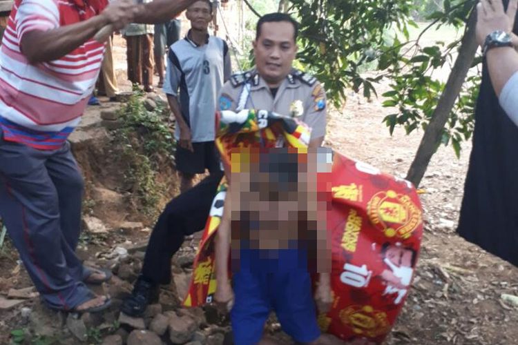 Seorang anggota polisi membantu menurunkan jenazah Barjo (74) yang ditemukan tewas gantung diri di Dukuh Batur, Desa Pelem, Kecamatan Bungkal, Kabupaten Ponorogo, Jawa Timur, Rabu ( 21/6/2017).