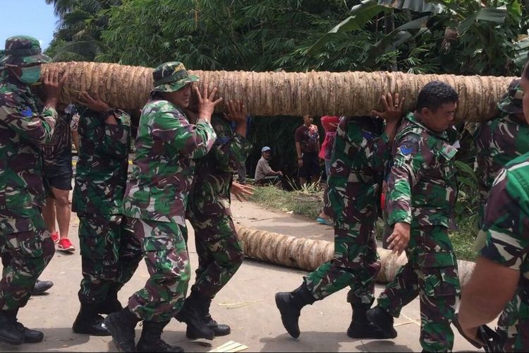 Prajurit Marinir dan warga bergotong royong mengangkat batang pohon kelapa untuk membuat jembatan darurat di Jalan Way Ratai, Pesawaran. Jembatan itu berada di jalan utama menuju sejumlah lokasi pariwisata di Pesisir Teluk Lampung.