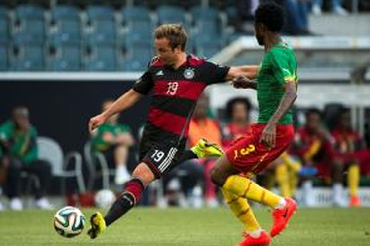 Gelandang Jerman, Mario Goetze (kiri) saat berusaha melepaskan tendangan di tengah kawalan pemain Kamerun, Nicolas Nkoulou Vie pada laga uji coba di Stadion Borussia Park, Minggu atau Senin (2/6/2014) dini hari WIB. 