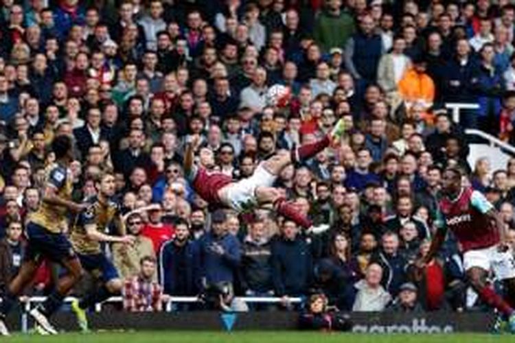 Aksi akrobatik striker West Ham United, Andy Carroll, pada laga versus Arsenal di Boleyn Ground, Sabtu (9/4/2016). 