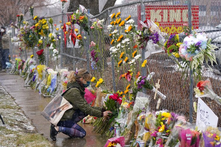 Seorang pelayat meninggalkan karangan bunga di sepanjang pagar yang dipasang di sekitar tempat parkir tempat penembakan massal terjadi di toko kelontong King Soopers Selasa, 23 Maret 2021, di Boulder, Colorado.