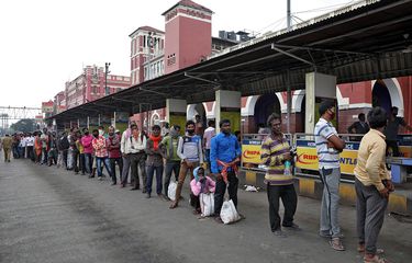 Para pekerja migran menunggu dalam antrean untuk menerima makanan gratis di luar stasiun kereta Howrah setelah Pemerintah India memerintahkan lockdown nasional untuk membatasi penyebaran penyakit virus corona (COVID-19), di Kolkata, India, Rabu (25/3/2020).