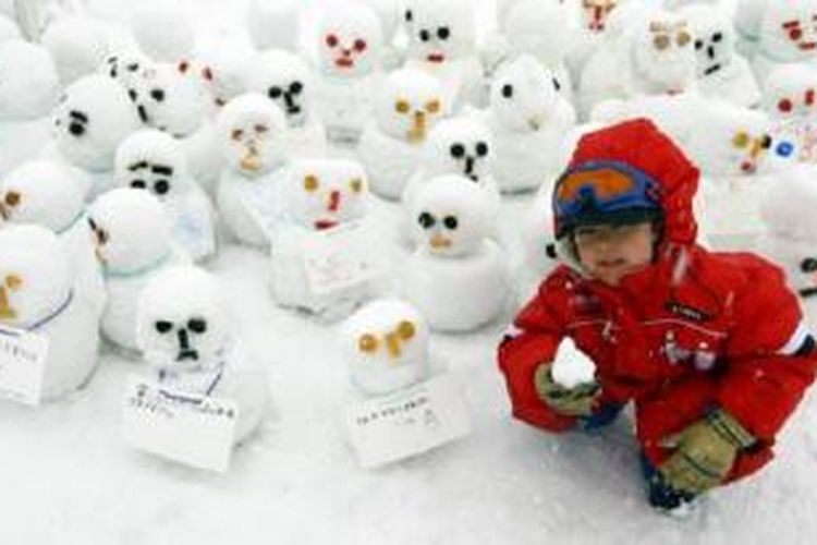 Membuat patung dari salju, seperti yang dilakukan seorang bocah di Jepang ini, menjadi pemandangan lumrah saat salju datang. 