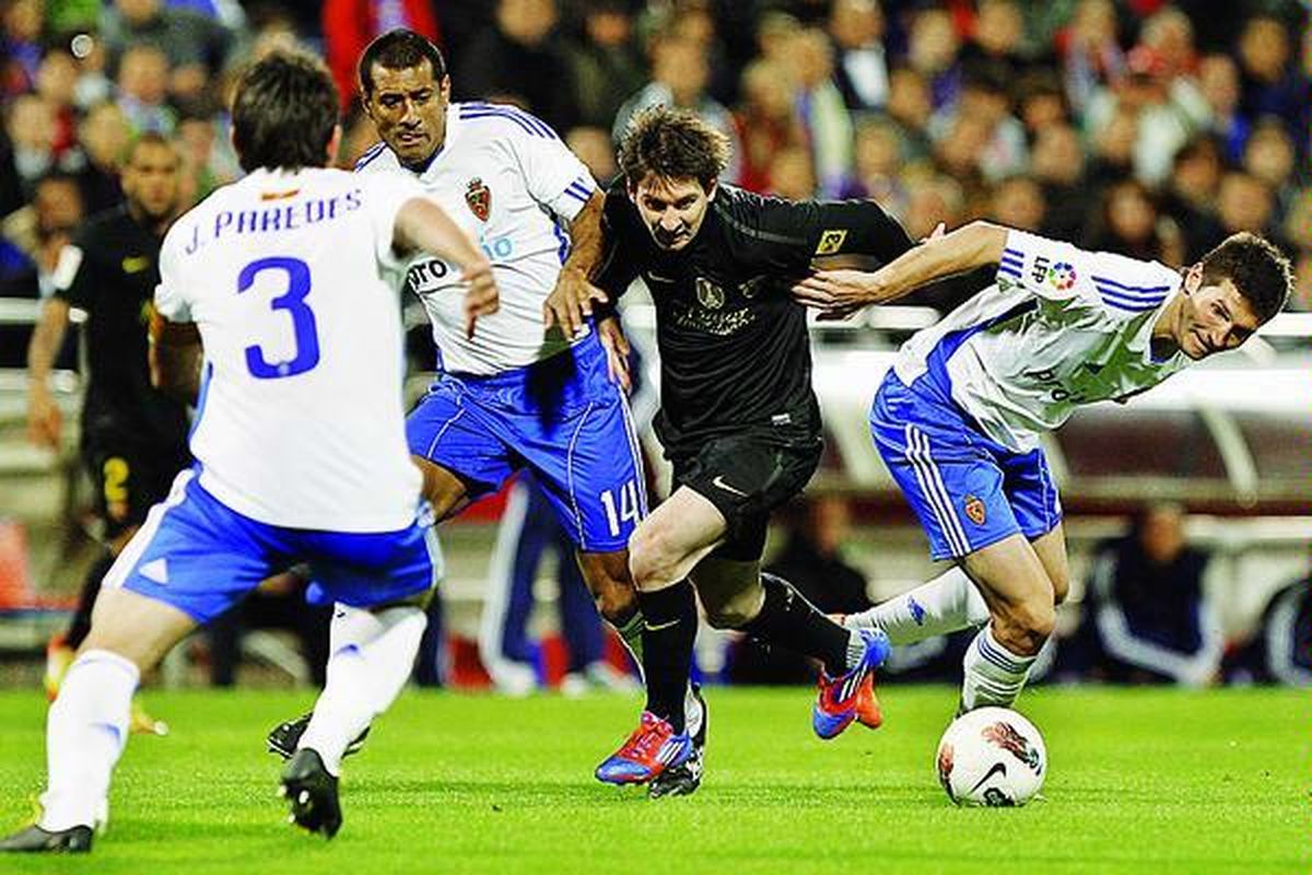 Penyerang Barcelona, Lionel Messi (tengah), berebut bola dengan pemain bertahan Real Zaragoza, Da Silva (kiri) dan Alvarez, pada lanjutan Liga Spanyol, Minggu (8/4), di Stadion La Romareda. Barcelona menang 4-1.