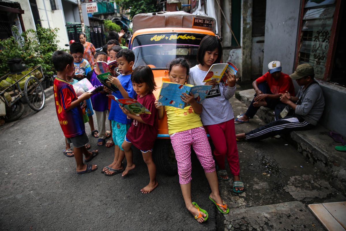 Anak-anak membaca buku di bemo perpustakaan di Jalan Karet Pasar Baru Barat II, Tanah Abang, Jalarta Pusat, Jumat (7/12/2018). Pak Sutino (58) adalah sopir bemo yang merintis bemo tuanya menjadi perpustakaan keliling bagi anak-anak sejak tahun 2013.  Pak Sutino (58) adalah sopir bemo yang merintis bemo tuanya menjadi perpustakaan keliling bagi anak-anak sejak tahun 2013.