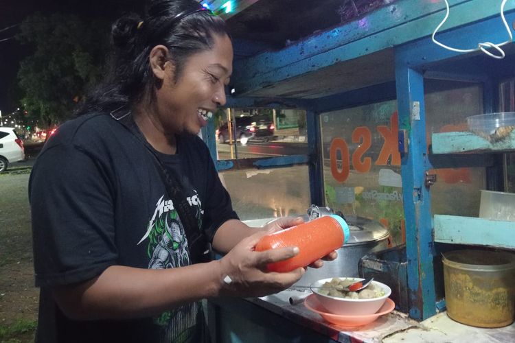 Sulismono alias Mono sedang menyajikan semangkuk bakso untuk pembelinya pada Selasa (21/10/2025) malam. Mono saat kerap disebut mirip dengan Komika Praz Teguh oleh pembelinya.