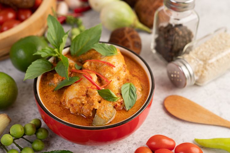 Seporsi kari ayam India dengan warna keemasan yang kaya rempah, disajikan dengan nasi basmati dan roti naan