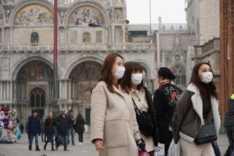 Turis yang mengenakan masker melindungi dari paparan virus corona mengunjungi Piazza San Marco, di Venesia, Italia, 24 Februari 2020. 