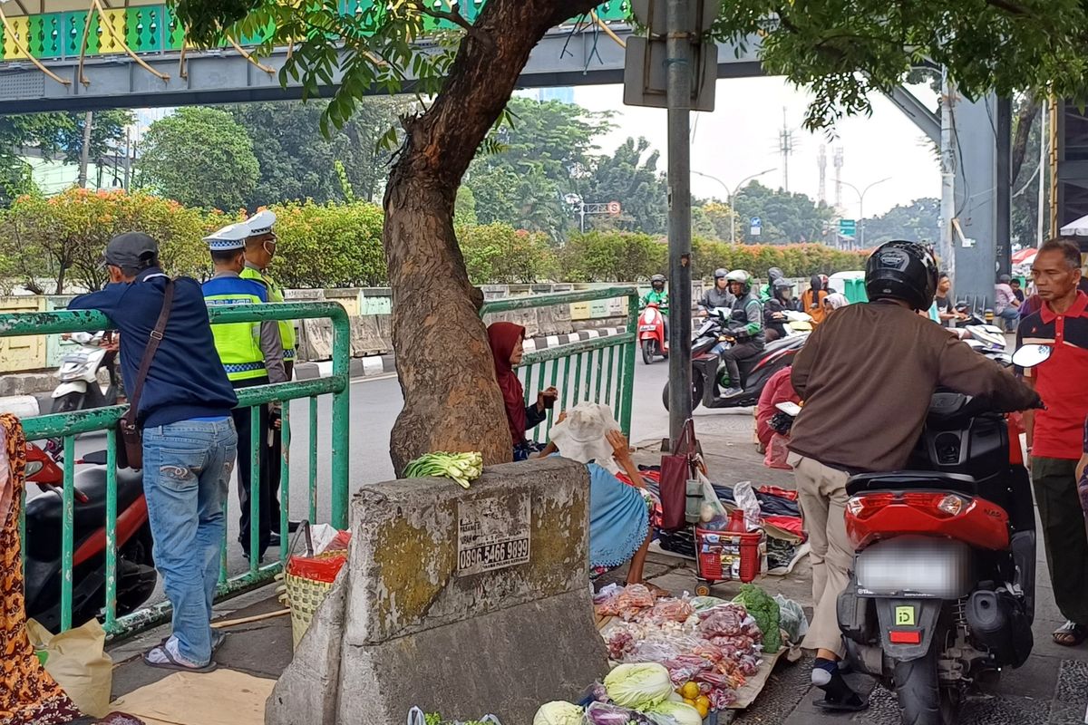 Seorang pengendara motor berpura-pura menuntun kendaraannya di atas trotoar supaya tak kena tilang ketika lawan arah di dekat Stasiun Pasar Minggu, Jakarta Selatan, Kamis (21/9/2023).