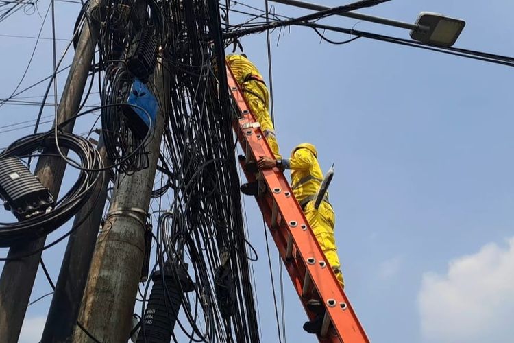 Petugas merapikan kabel fiber optik yang menjuntai di Jalan KS Tubun, Palmerah, Jakarta Barat, Kamis (10/8/2023). 
