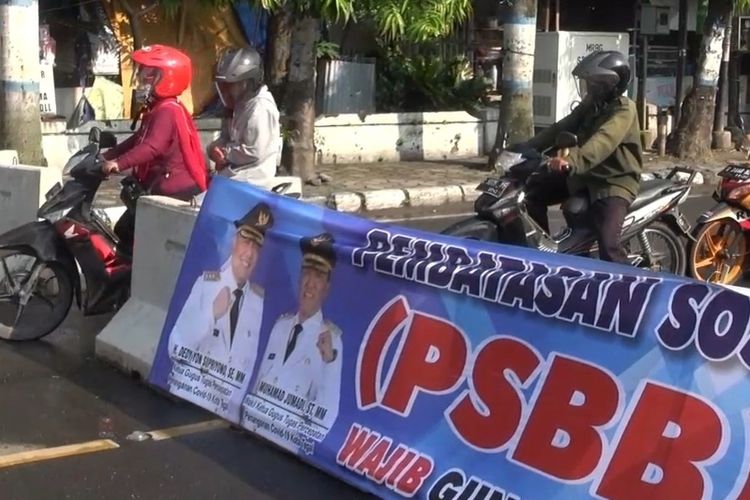 Pengendara sepeda motor menerobos blokade beton di Jalan Sultan Agung, Kota Tegal, di hari kedua pelaksanaan PSBB, Jumat (24/4/2020).