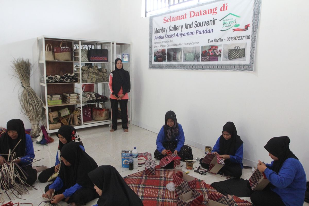 Tokoh penggerak KBA Desa Pantai Cermin Kanan dan pencetus Kelompok Perempuan Kanan Kreatif (KPKK) Eva Harlia (tengah) bersama anggota KPKK saat membuat anyaman di rumah kreasi anyaman pandan Menday Gallery and Souvenir.