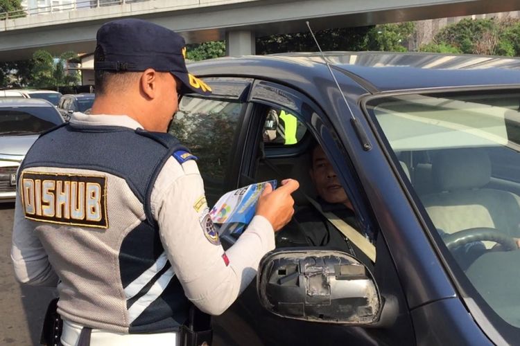 Petugas melakukan sosialisasi uji coba ganjil genap untuk lalu lintas Asian Games 2018 di Jalan Tomang Raya pada Senin (2/7/2018).