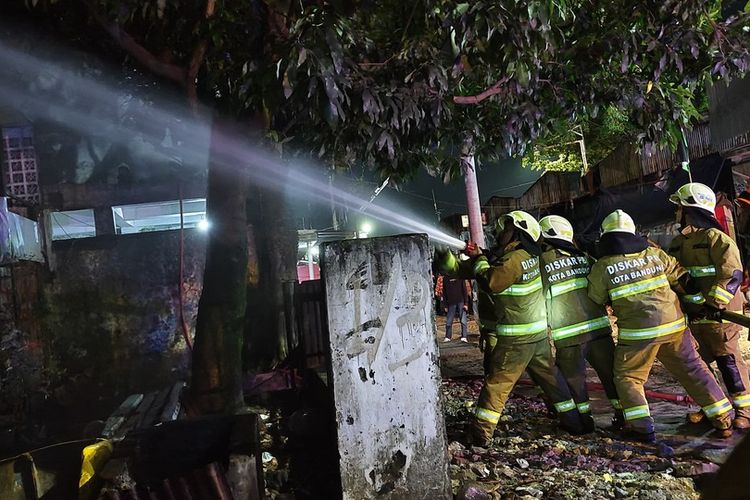 Petugas Diskar PB Kota Bandung saat memadamkan api yang melahap gedung bahan kimia dan bangunan bekas hotel di Kota Bandung, Minggu (14/7/2024) dini hari.