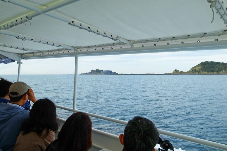 Wisatawan melihat Gunkanjima dari atas kapal. 