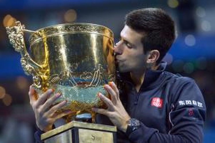 Petenis Serbia, Novak Djokovic, mencium trofi juara China Terbuka yang didapat setelah mengalahkan Tomas Berdych pada laga final di National Tennis Center, Beijing, Minggu (5/10/2014). Djokovic menang 6-0, 6-2.