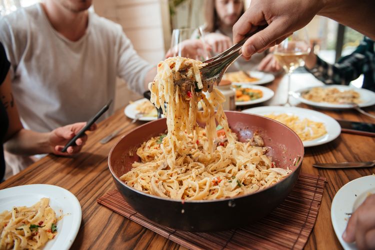 Ilustrasi sekelompok orang makan pasta di rumah. 