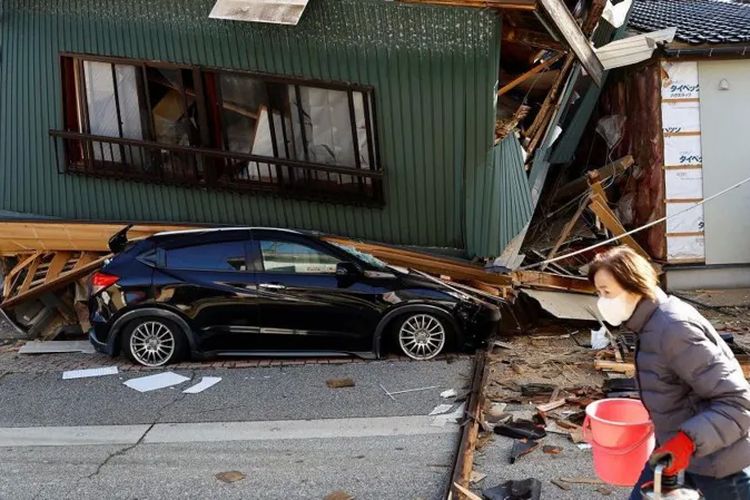 Sebuah mobil terjepit rumah yang ambruk akibat gempa di Nanao, Prefektur Ishikawa, Jepang, pada 2 Januari 2024.