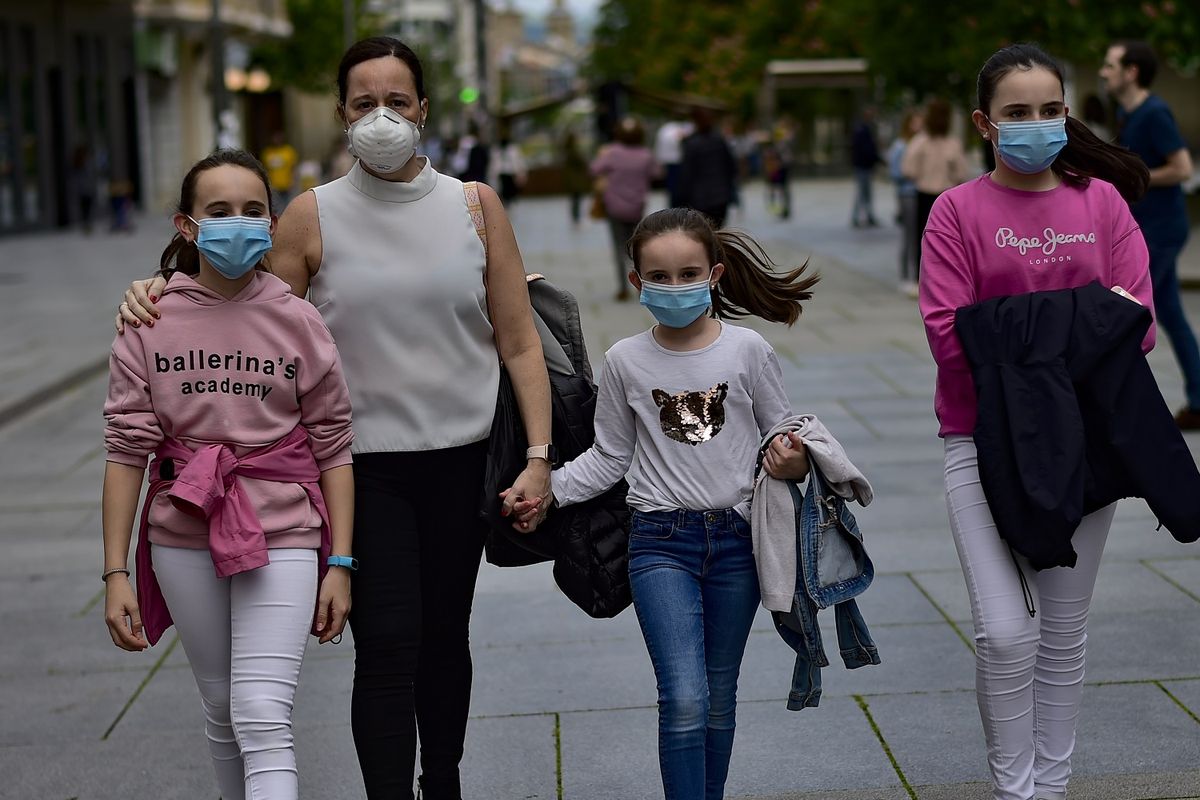Sebuah keluarga mengenakan masker untuk melindungi mereka dari virus corona, berjalan di Carlos III Pamplona, utara Spanyol, pada 27 April 2020. Pada Minggu, anak-anak berusia di bawah 14 tahun diizinkan keluar rumah sebagai bagian dari upaya pemerintah melonggarkan lockdown.
