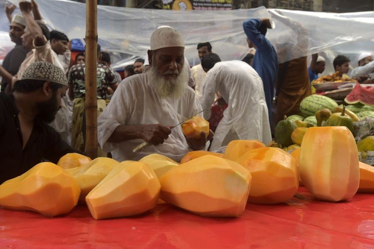 Sejumlah buah pepaya yang sudah dikupas menjadi salah satu pilihan jajanam berbuka di pasar Chawkbazar di Dhaka, Bangladesh, Jumat (24/3/2023).
