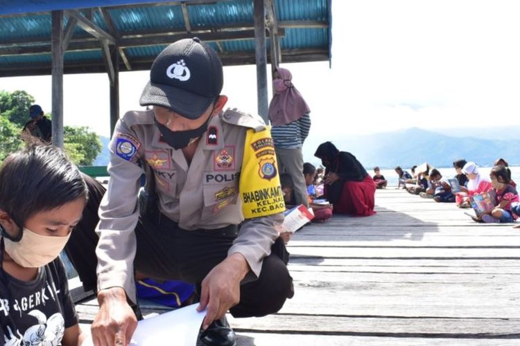 Aipda Resky, anggota Bhabinkamtibmas Kelurahan Nalu saat sedang mengajar seorang anak belajar membaca. Kamis, 6 Agustus 2020.