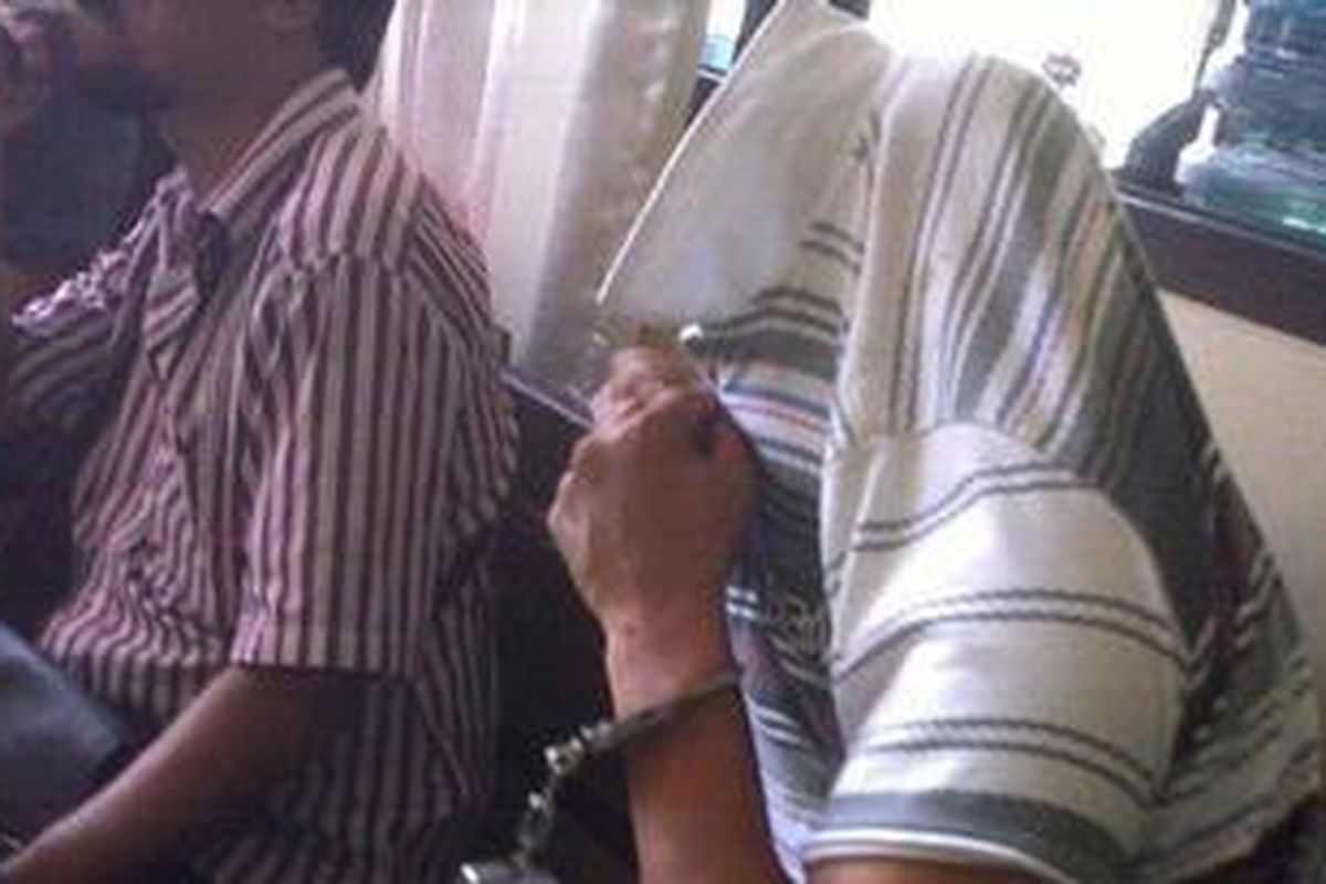 Tersangka Rudi Saputra Siregar, 30, Narapidana Lapas Bangli yang tertangkap karena akan mengedarkan narkoba di luar Lapas menutupi wajahnya saat diperiksa di Mapolres Badung, Senin (9/5/2011).