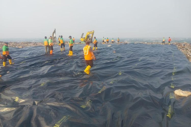 Sejumlah petugas menutup area timbunan sampah menggunakan media pelindung di Zona 2 TPST Bantargebang, Kota Bekasi, sebagai tahap awal penerapan sistem controlled landfill, Rabu (22/7/2026).