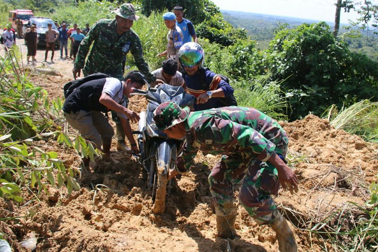 TNI bantu pengguna kendaraan roda dua lewati lokasi jalan tertimbun longsor dengan cara mengangkat,  Selasa (19/12/2017).