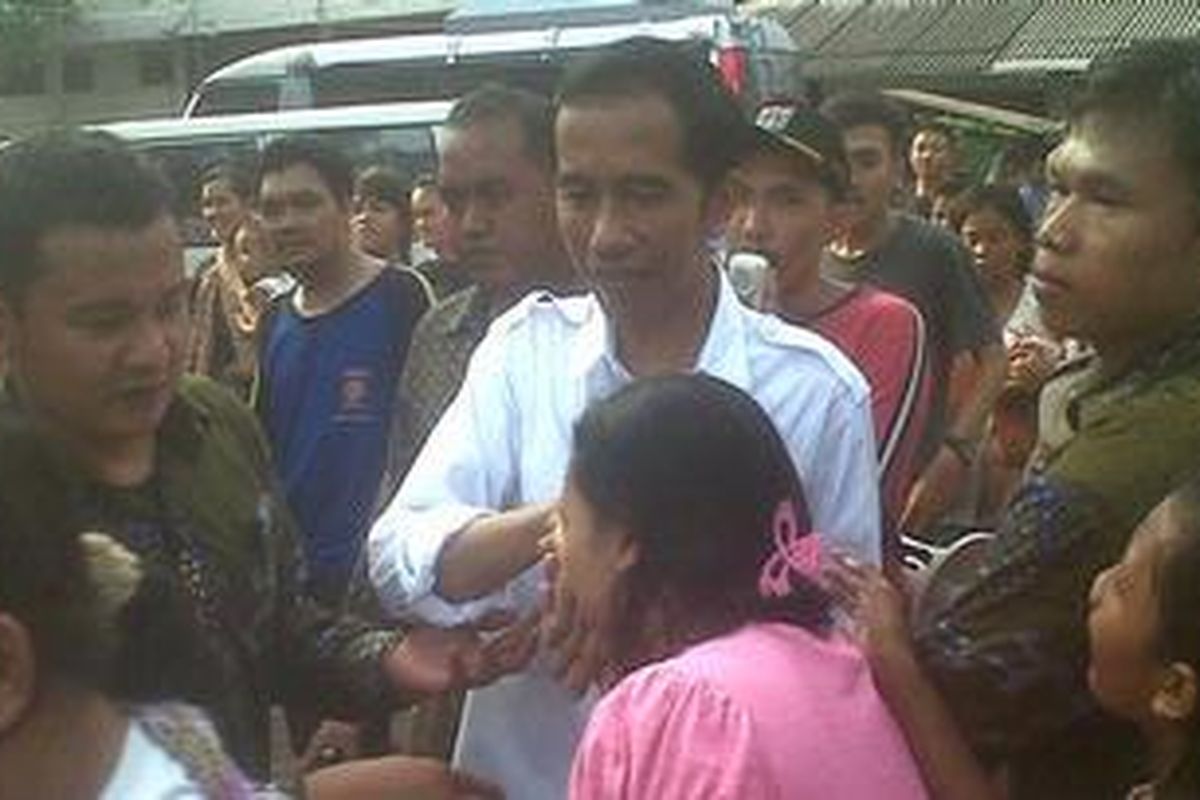 Gubernur DKI Jakarta Joko Widodo dikerubuti dan disalami warga korban kebakaran di GOR Pademangan, Jakarta Utara, Senin (25/2/2013).