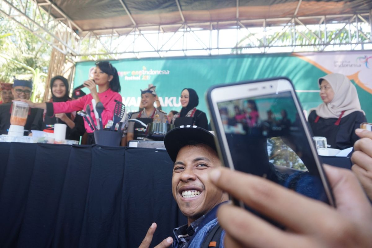 Seorang pengunjung sedang selfie dengan latar belakang Farah Quinn yang sedang memasak di Festival Banyuwangi Kuliner Kamis (12/4/2018)